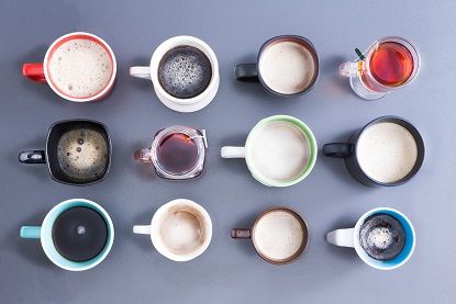 Konceptualno image depicting the Time for your daily dose of caffeine with an overhead view of a neat arrangement of twelve different cups, mugs and glasses filled with hot fresh tea and coffee on grey